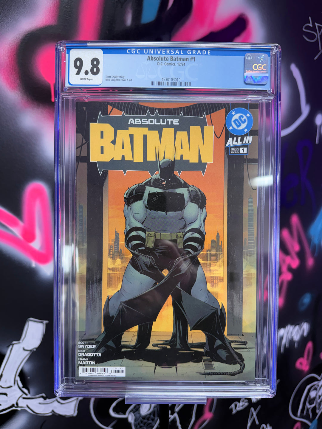 Comic book titled 'Absolute Batman' in a clear protective case with a colorful background.